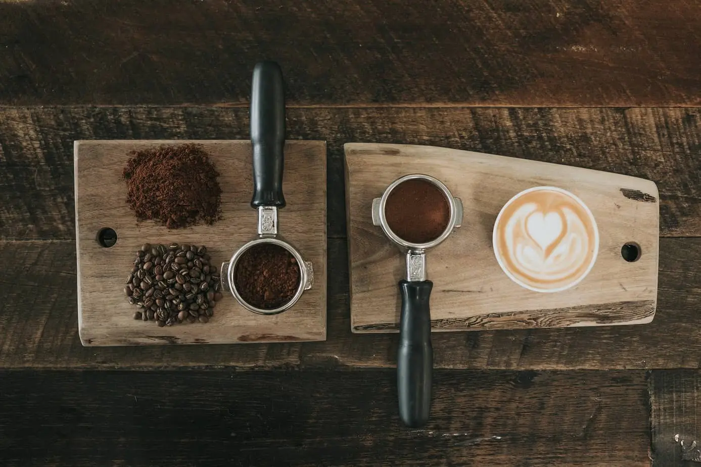 وصفات لتحضير حبوب البن وفنجان من القهوة على لوح خشبي.
