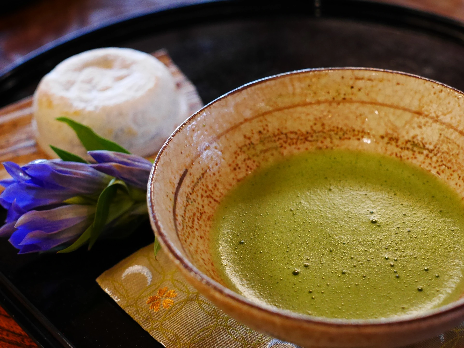 وعاء من الشاي الأخضر عليه زهرة ، لإبراز فوائد شرب الشاي الأخضر.