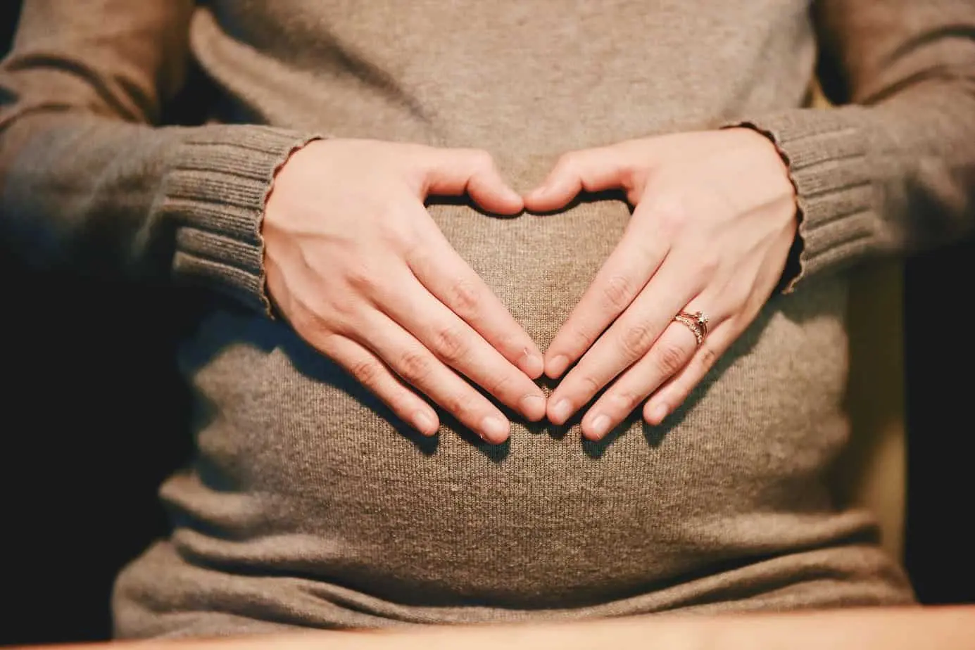 سيدة حامل تظهر شكل قلب بيديها وهي تدرك مخاطر تناول الشاي أثناء الحمل.