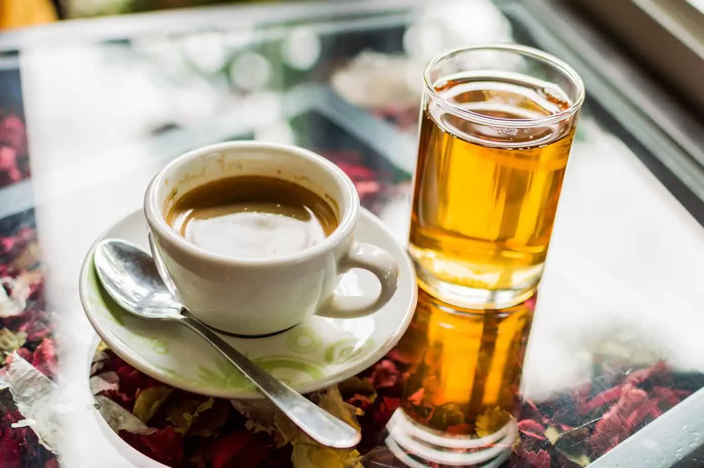 فنجان القهوة وكوب شاي أخضر على منضدة.