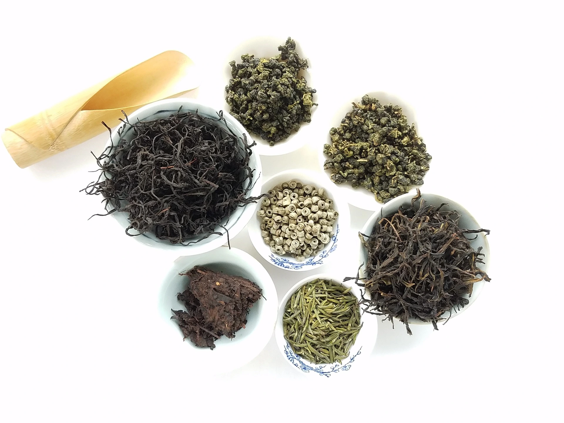 أنواع مختلفة من أوعية الشاي على خلفية بيضاء ، بما في ذلك الشاي الأخضر والأسود.