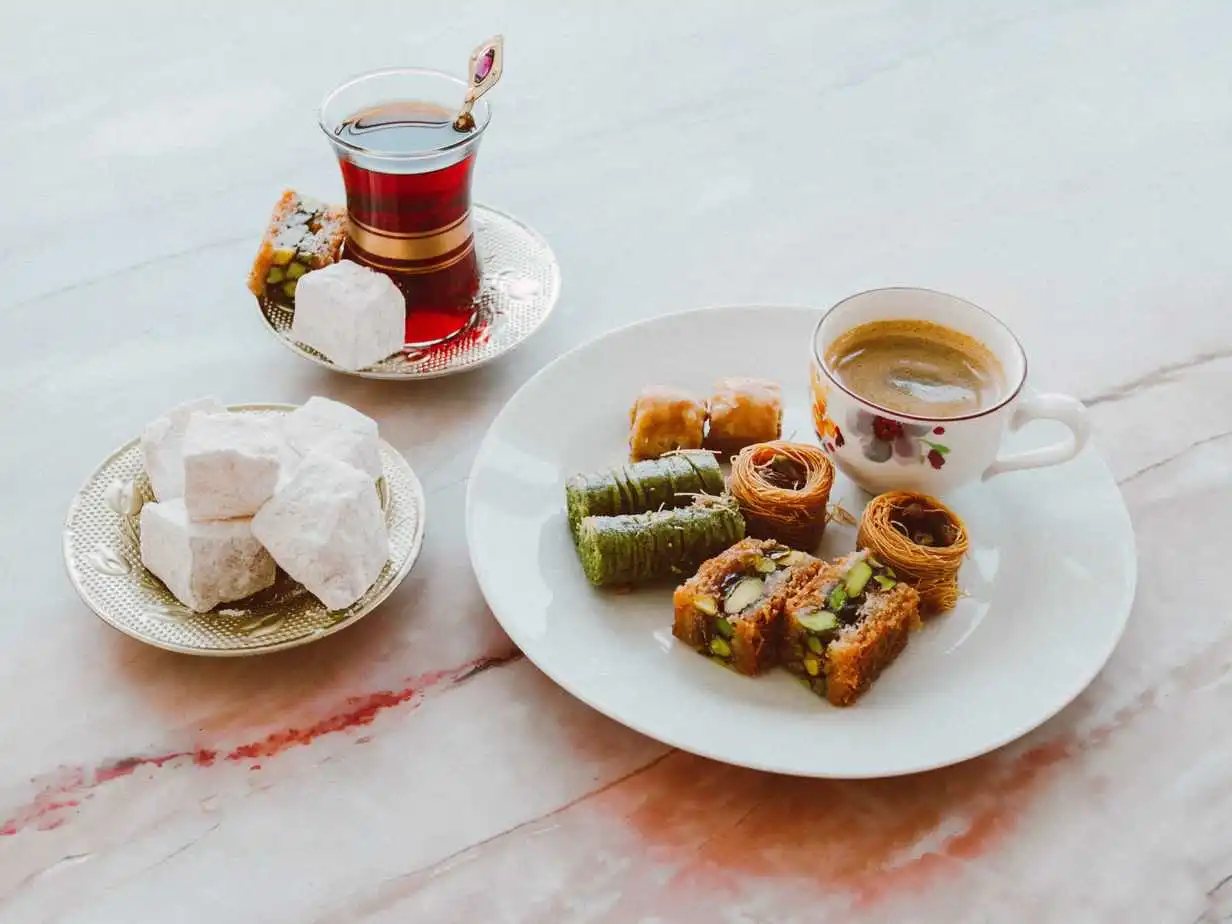 تقدم الحلويات والقهوة التركية على طاولة رخامية تجسد الشاي في الثقافة العربية.
