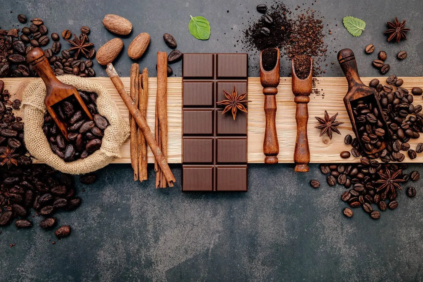 قطعة شوكولاتة وحبوب قهوة معروضة على لوح خشبي.