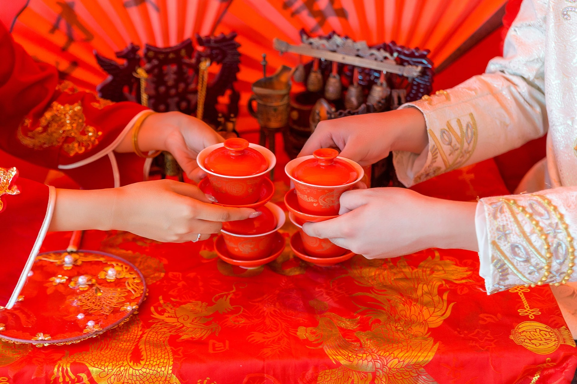 يستمتع شخصان صينيان بأنواع مختلفة من الشاي الصيني أثناء جلوسهما على طاولة حمراء.